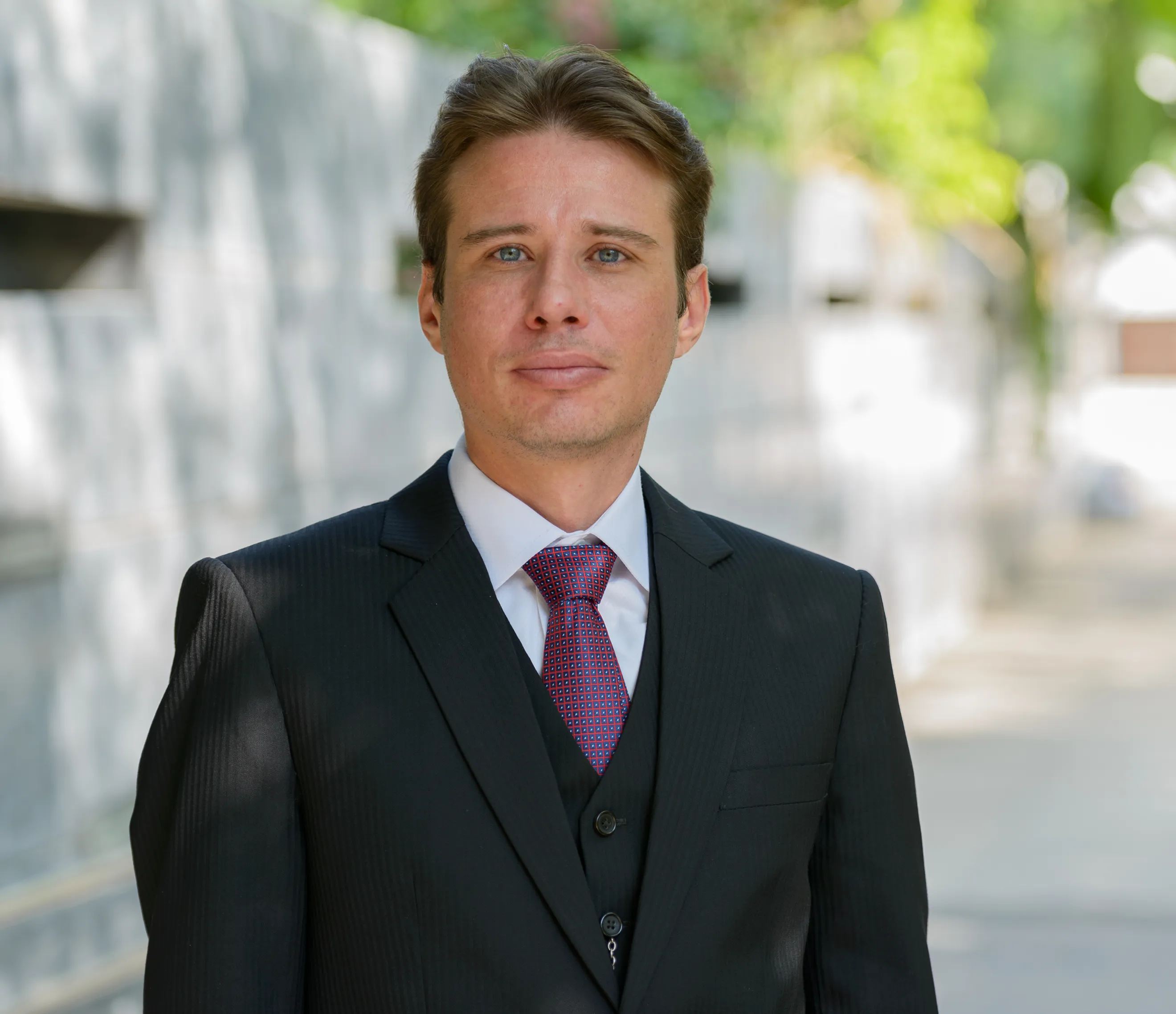 Professional man in a black suit, white shirt, and purple tie posing outdoors