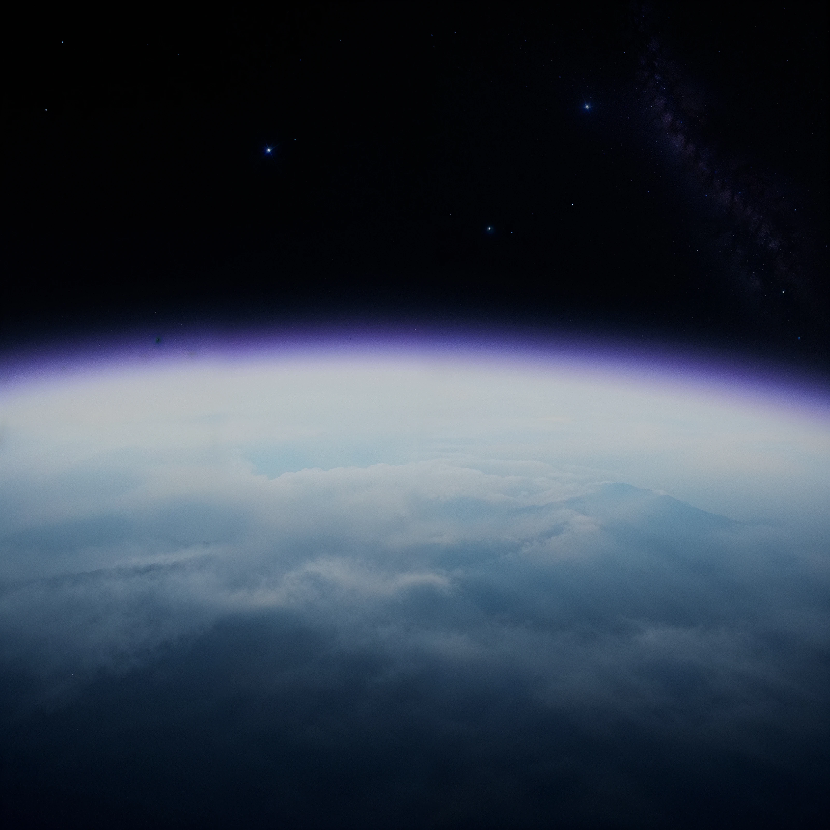 The curved horizon of Earth and cloud cover beneath a star-filled sky.