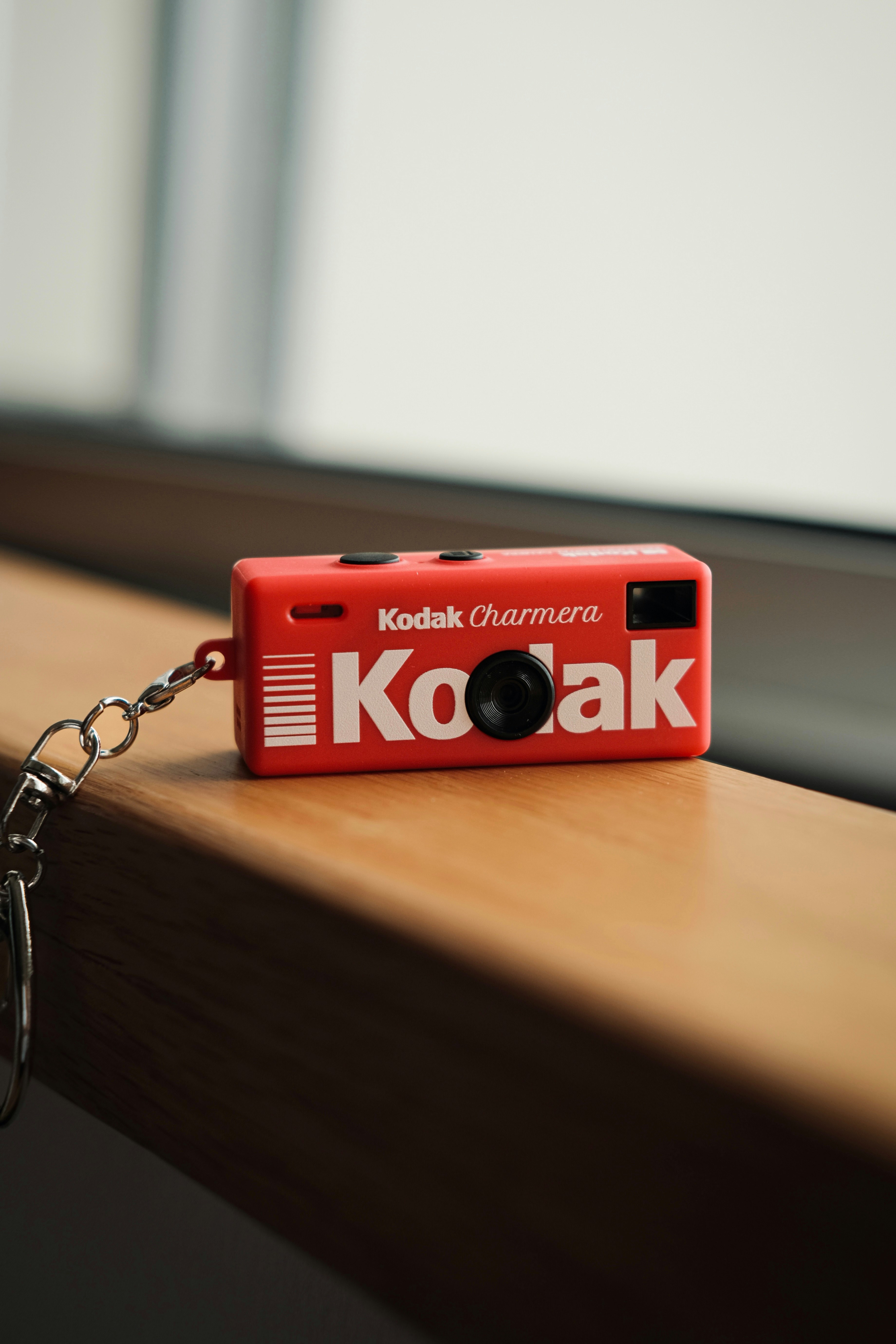 A small red kodak charmara camera on a wooden surface.