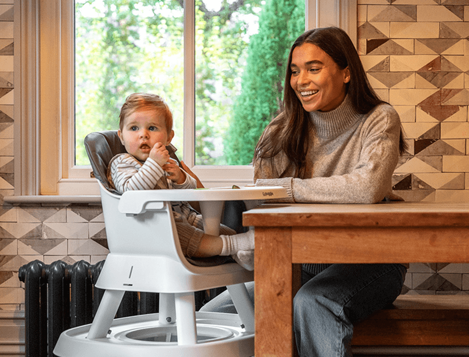 A young mum at home feeding her baby in a highchair