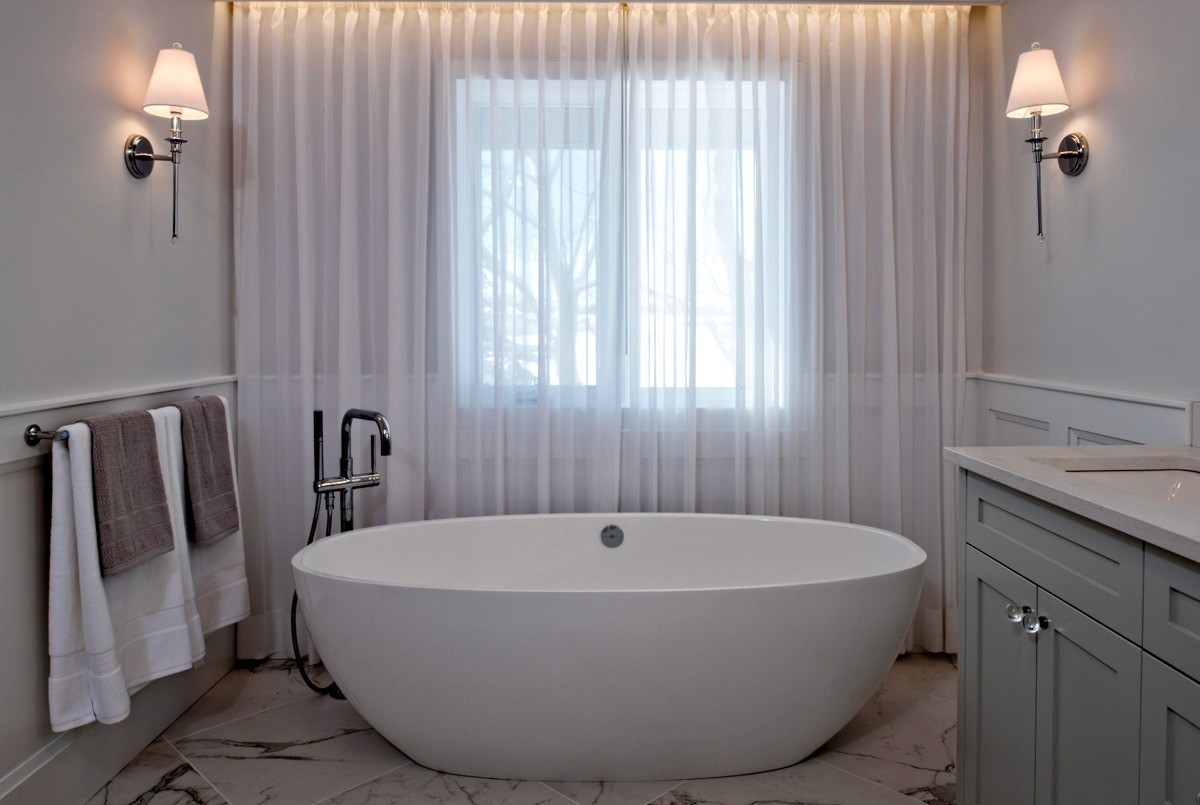 Image of Luxurious spa bathroom with freestanding tub, modern fixtures, and elegant window coverings by KHD Homes.