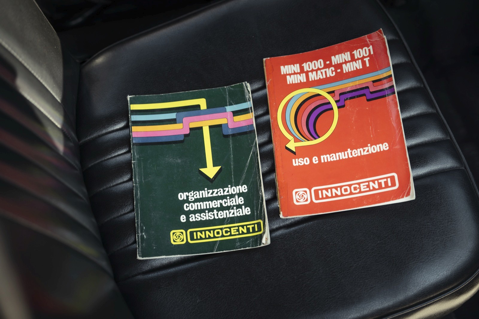 Two packages on a vehicle seat: one green and one red, each labeled with distinctive designs and text.