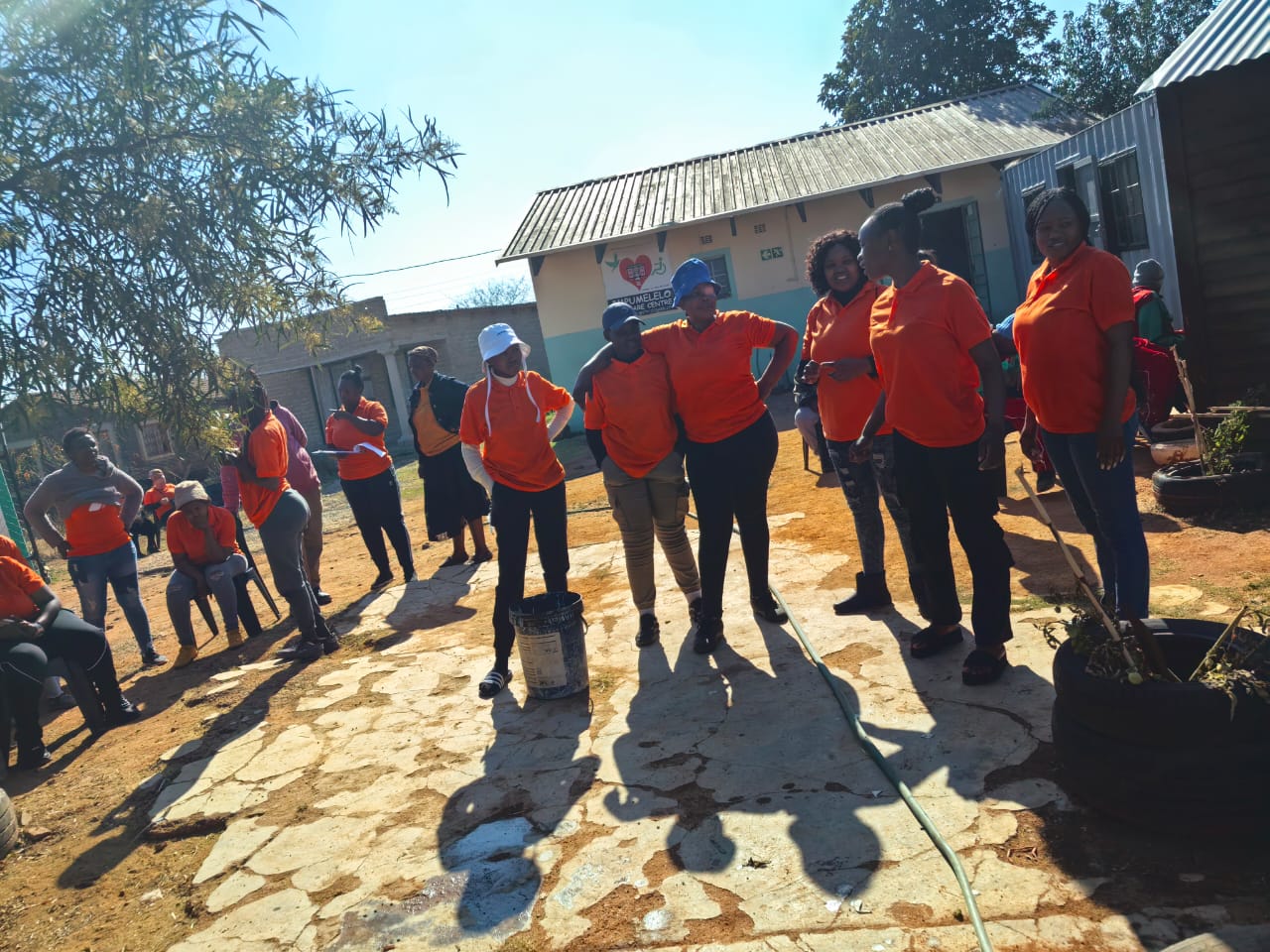 Smiling young man with short hair poses against a dark background, wearing a green button-up shirt.