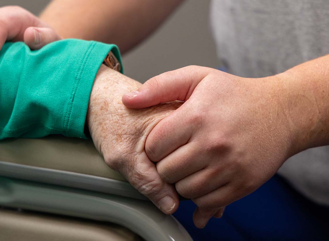 WTADS client MOSAIC leaning into care holding hands of a patient.