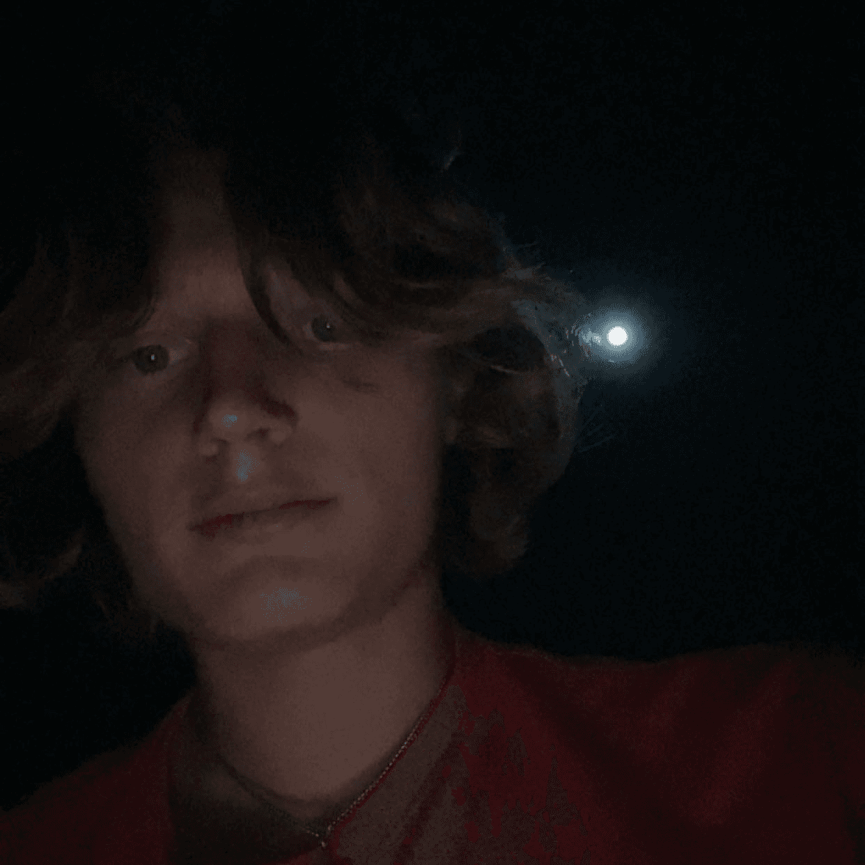 A person on a white shirt and black coat standing at the window indoor of the office