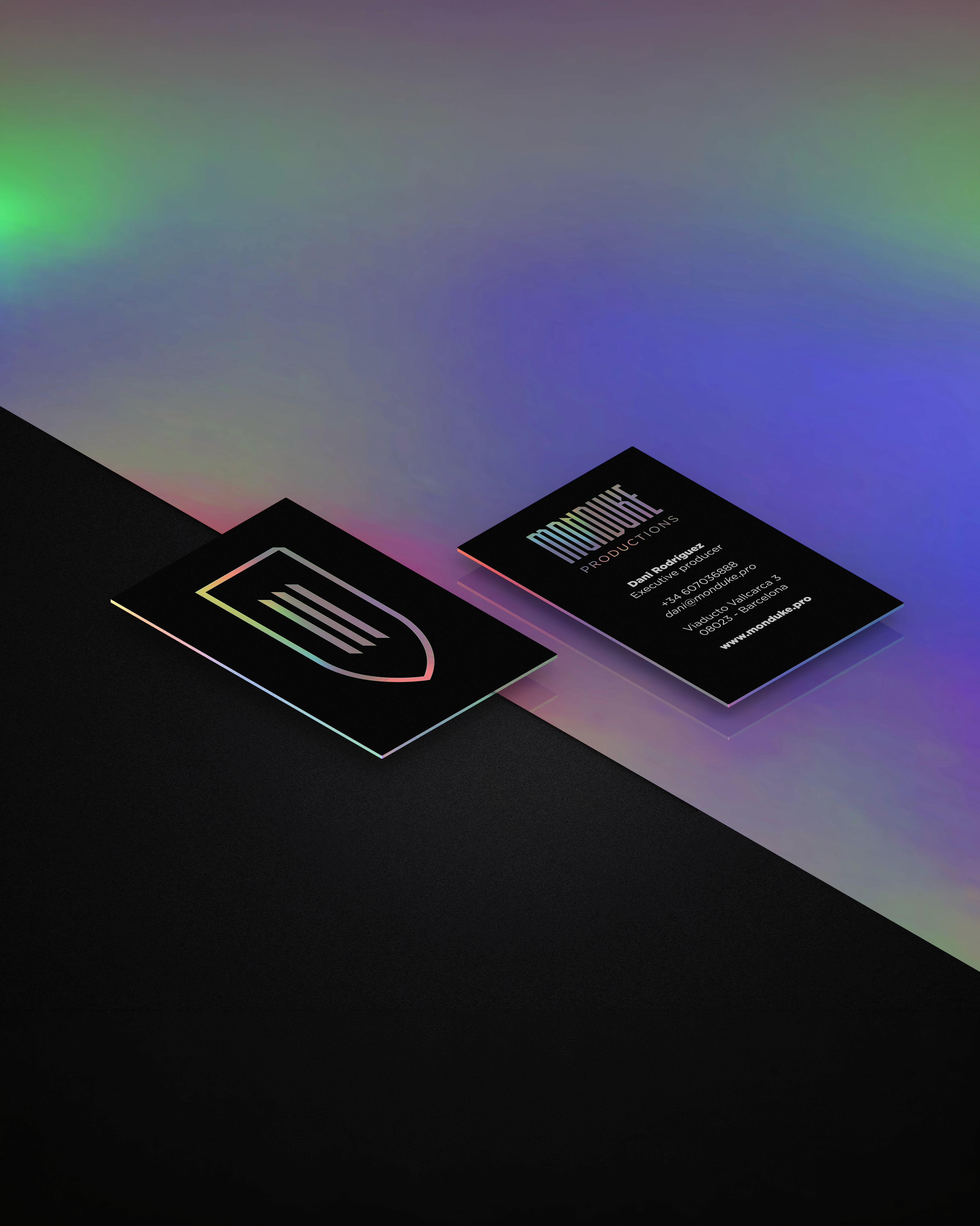 Monduke Productions holographic business cards with gradient shield logo on black, brand identity design by Sebastian Saavedra