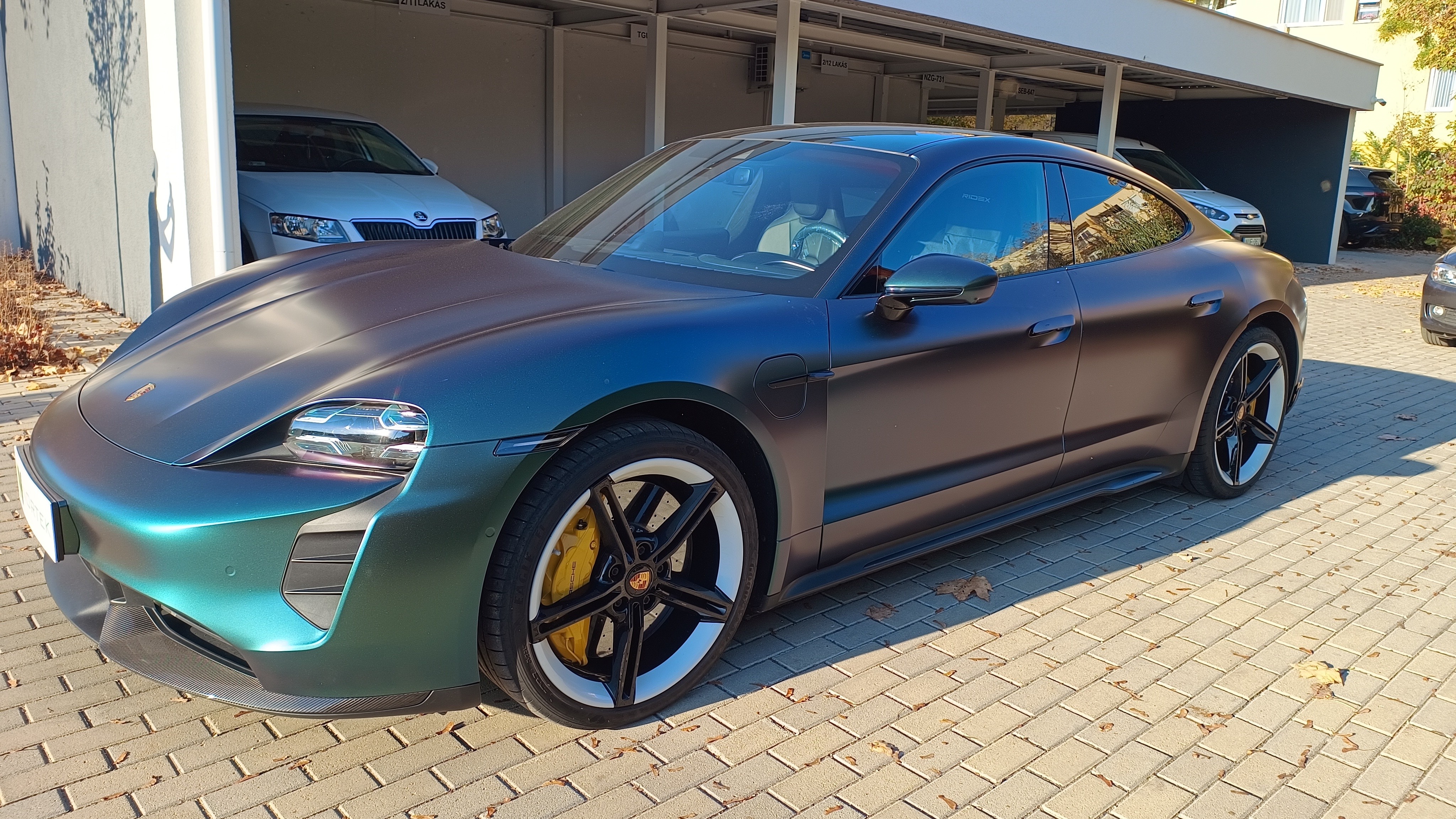 Különleges, színváltó (chameleon) matt autófóliával (wrap) átszínezett Porsche Taycan elektromos autó zöldes-lila árnyalatokban.