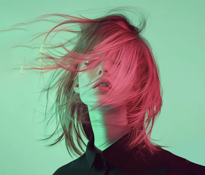 Against a green background, the girl dances with her red hair.