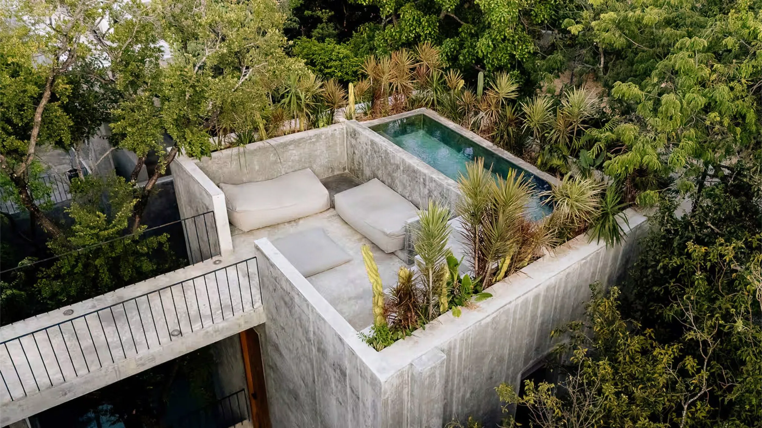 Aerial view of the private rooftop sanctuary with plunge pools and lounge areas surrounded by the Tulum jungle canopy.