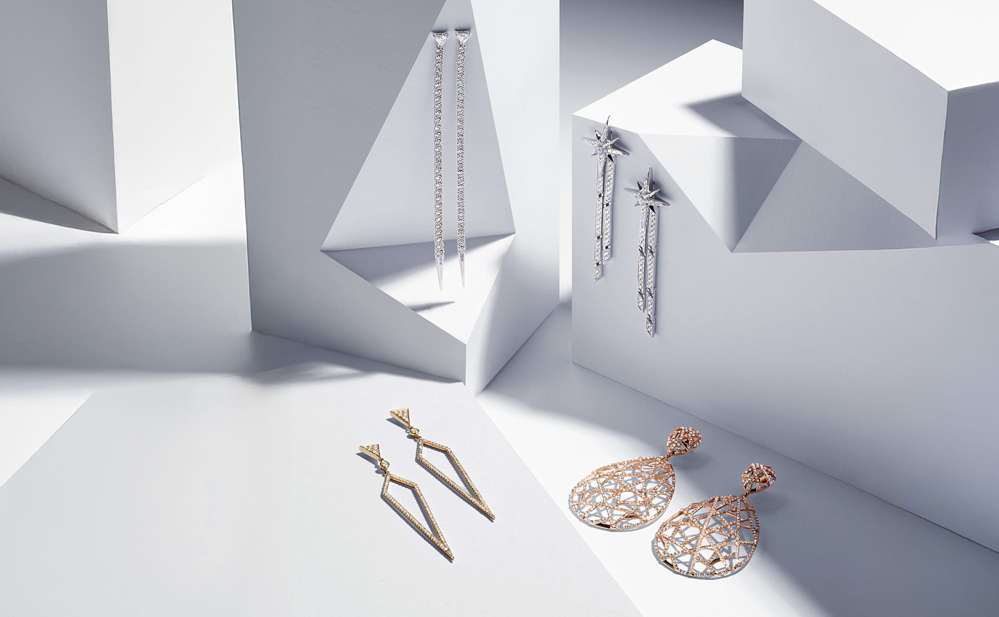 Elegant gold and silver earrings on geometric white display.