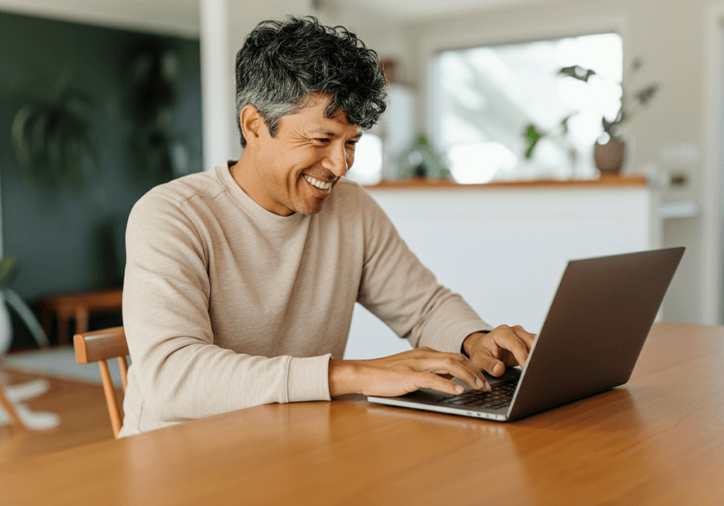 a man reviewing content on a laptop with a smile on his face