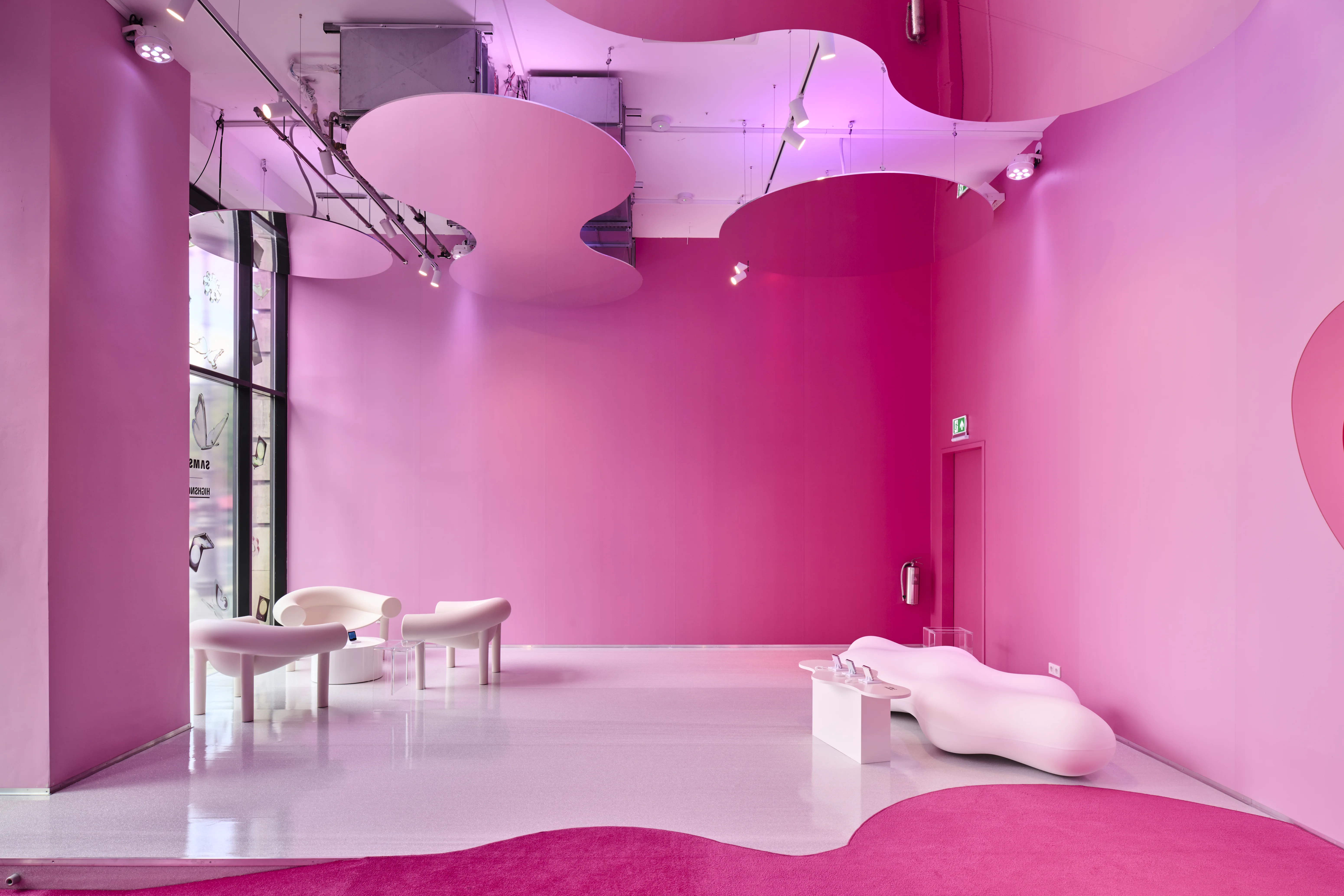 Monochrome pink room of the Samsung Flipside pop-up with cloud-shaped ceiling elements and organically shaped white loungers.