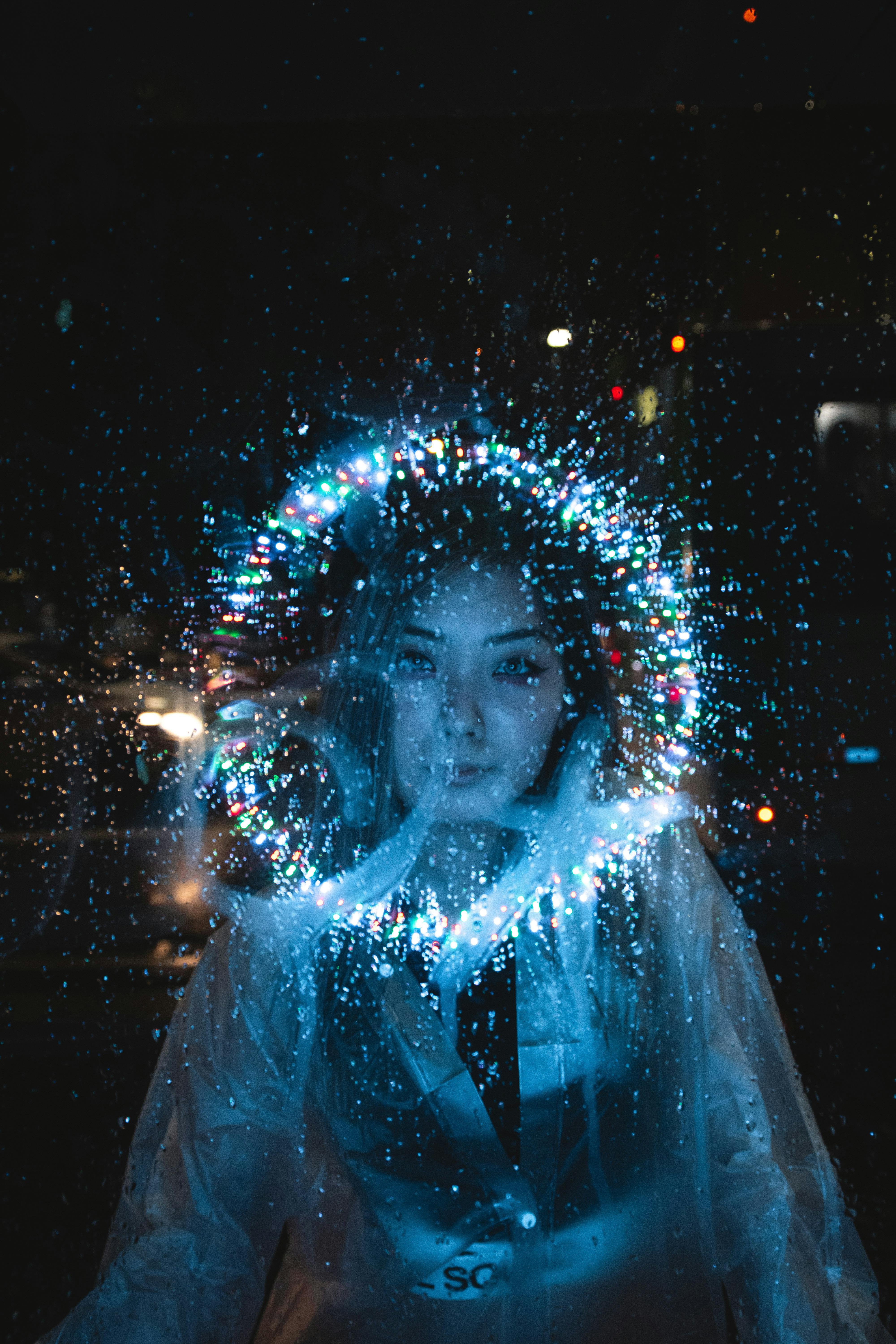 A woman gazing at the camera through a ring of lights in an otherwise dark room