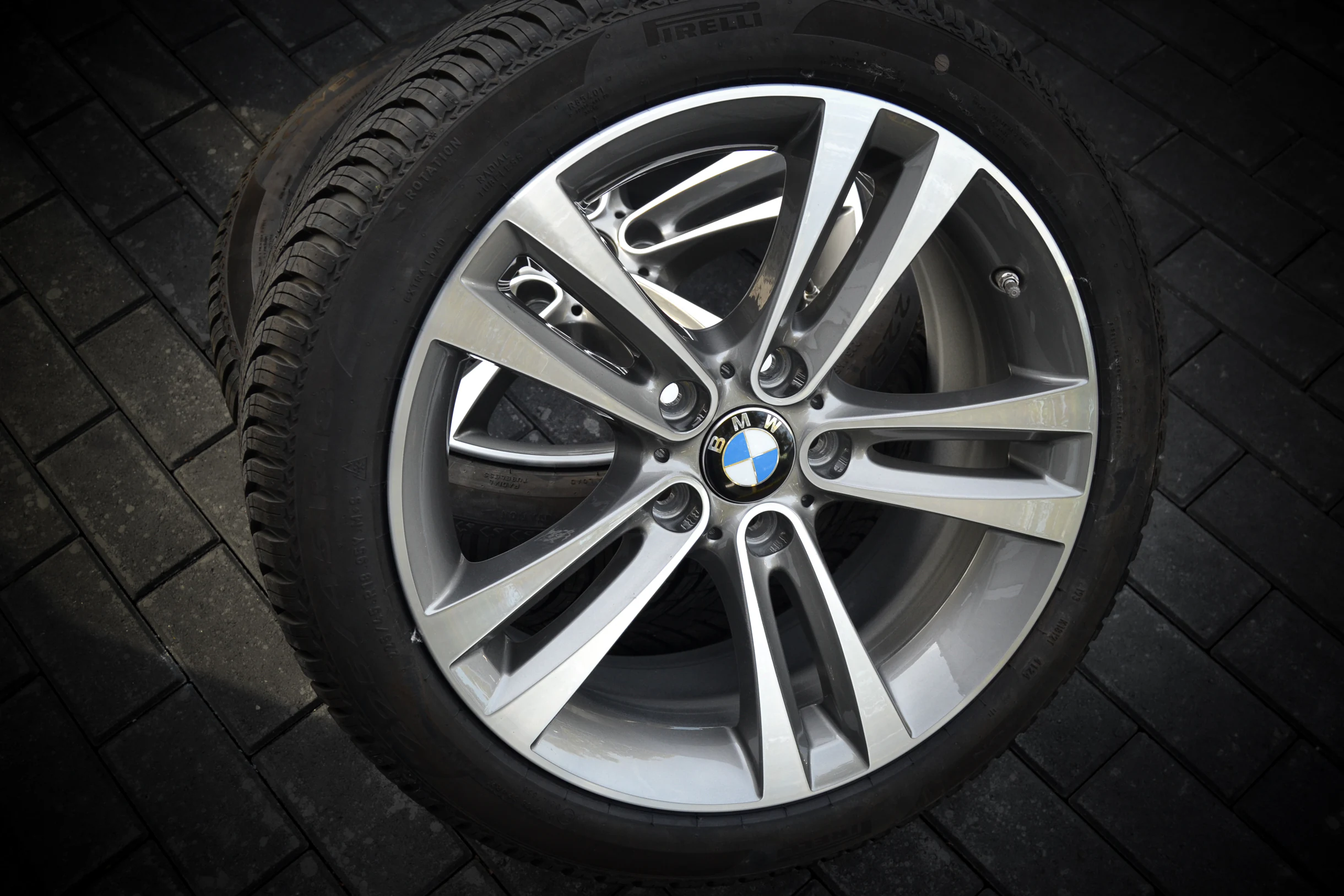 Silberfarbene BMW-Doppelspeichenfelge mit montiertem Reifen, Gesamtansicht bei AT Plus.