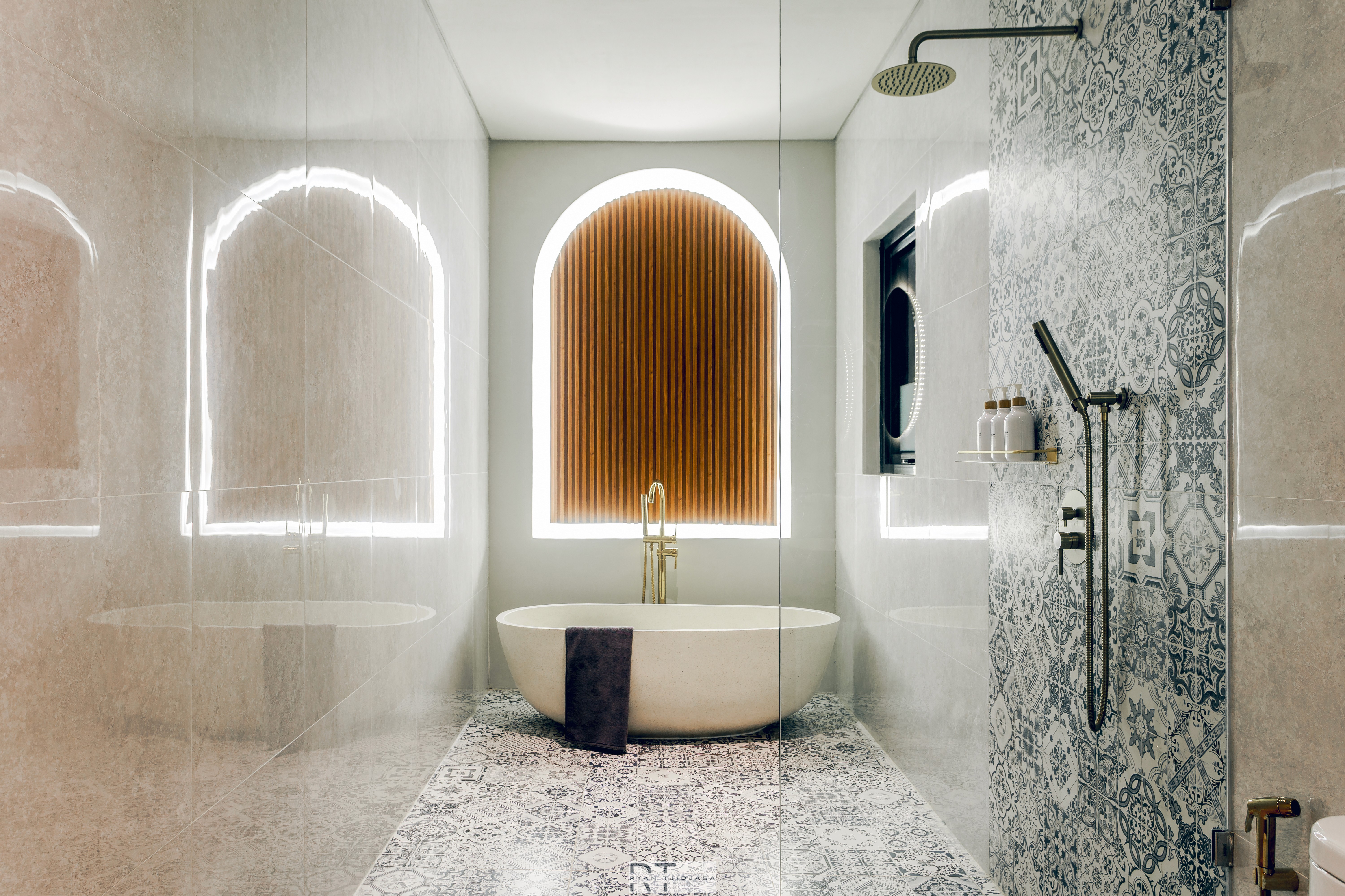 Freestanding bathtub with wood slat feature wall, arched backlit mirrors, patterned tile floor, and glass walk-in shower.