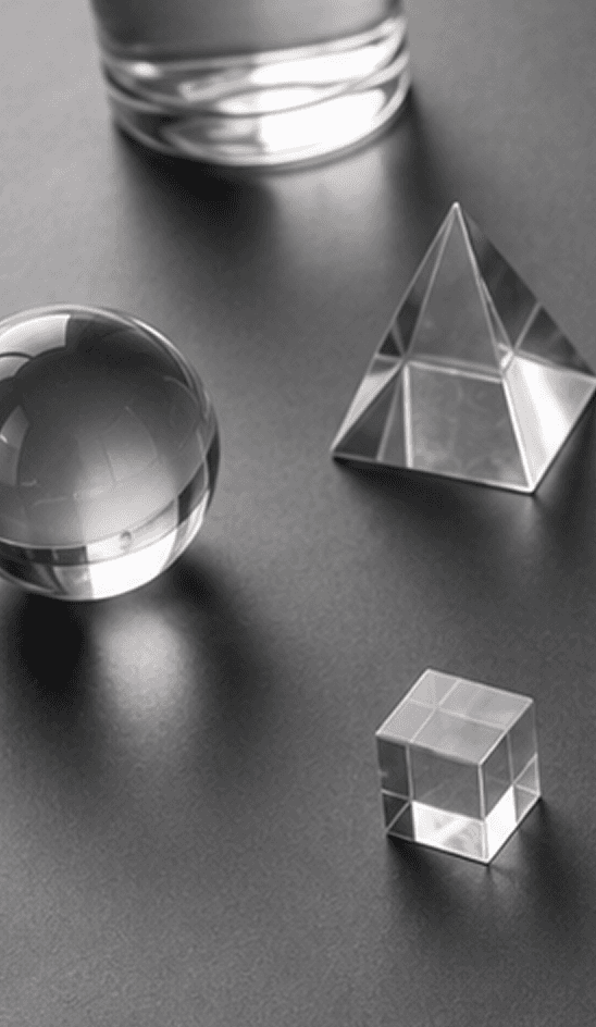 Glass sphere, cylinder, pyramid, and cube on an office desk