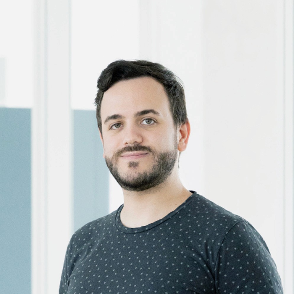 Woman playing paddle tennis, concentrating on her swing. A man watches from the sidelines.