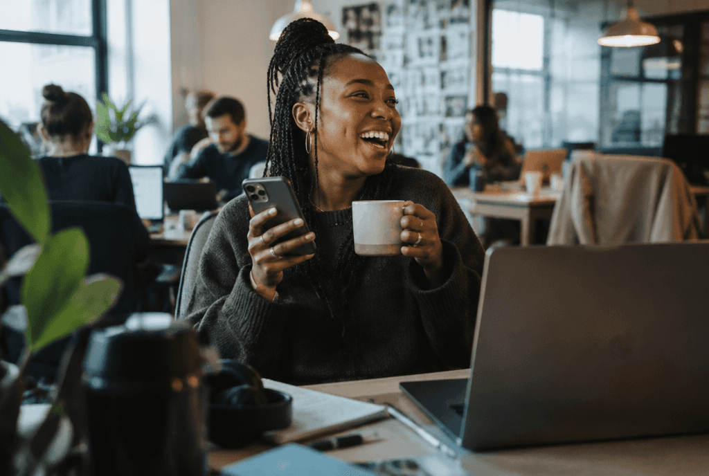 Marketer laughing with coffee while reviewing X ad engagement on a phone