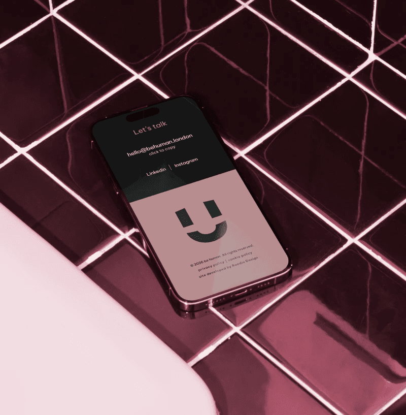 be human website open on a cell phone, sitting on a metallic burgundy tile sink