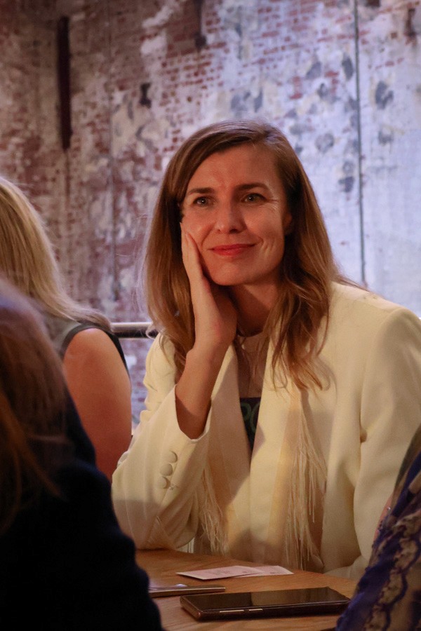 woman sits at table listening to her peers