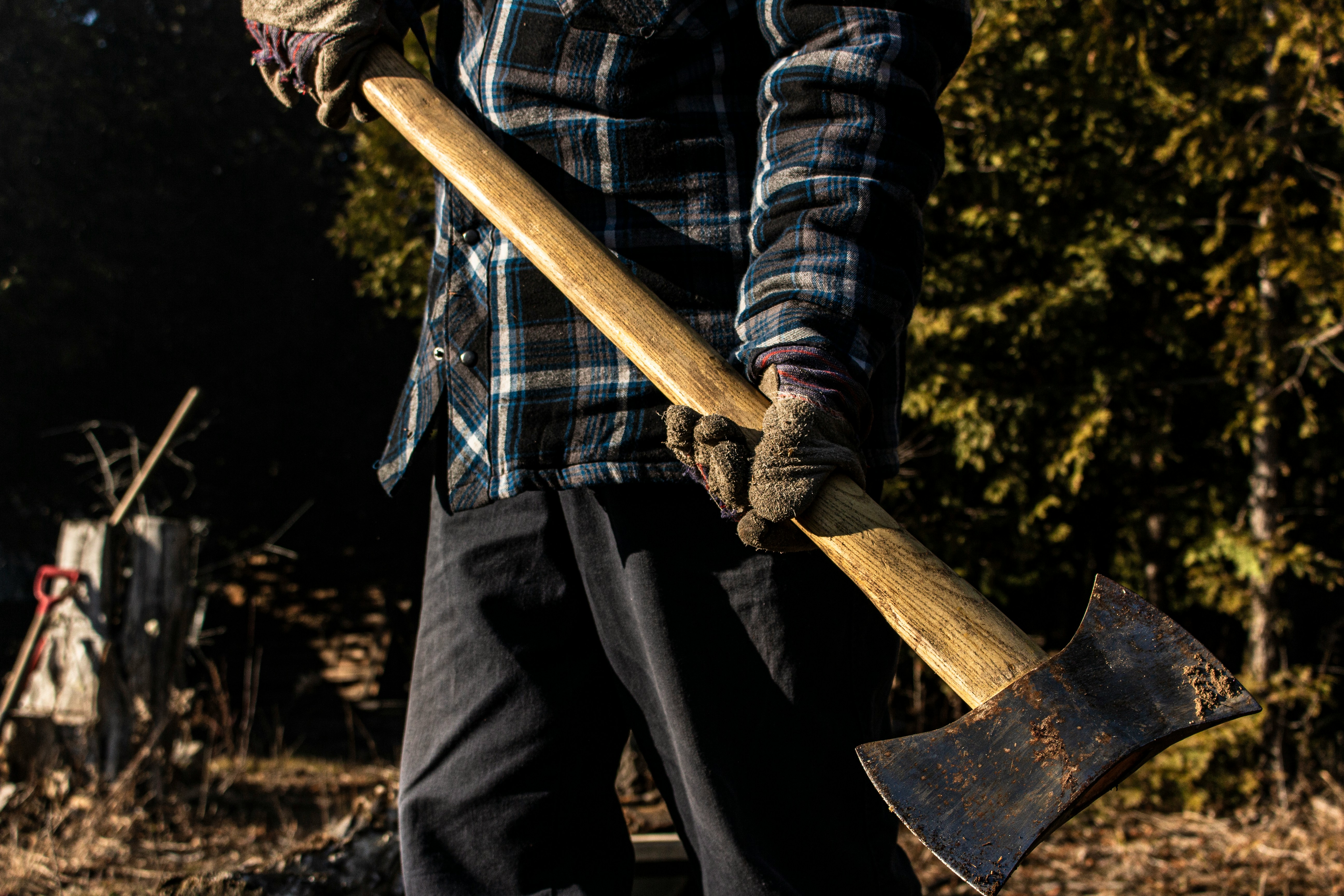 A coach in flannel and gloves holding a long axe