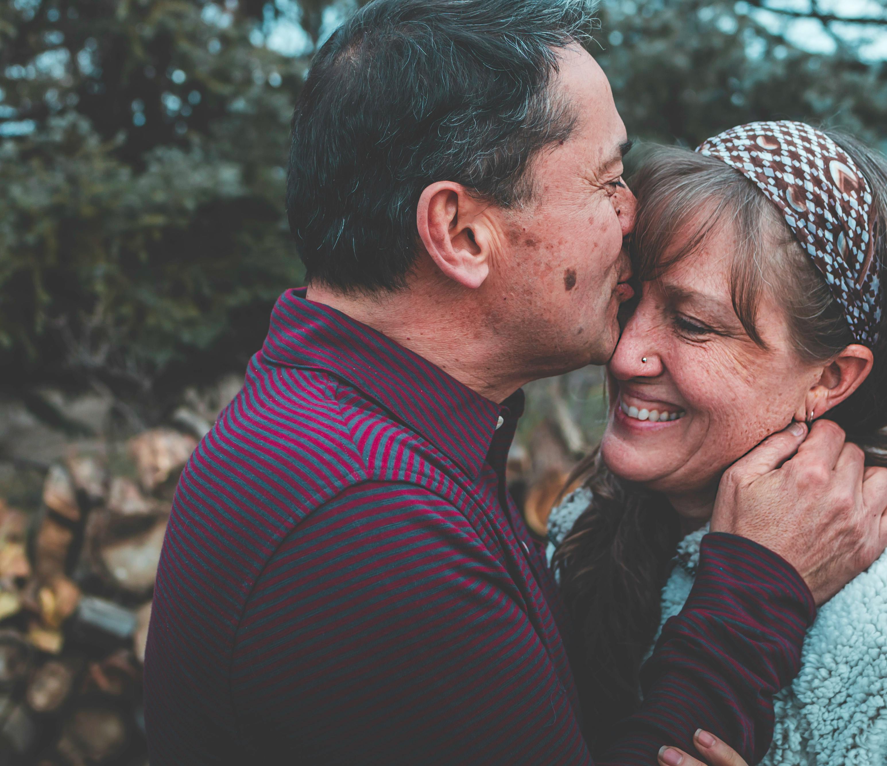 Older man kissing older woman on forehead 