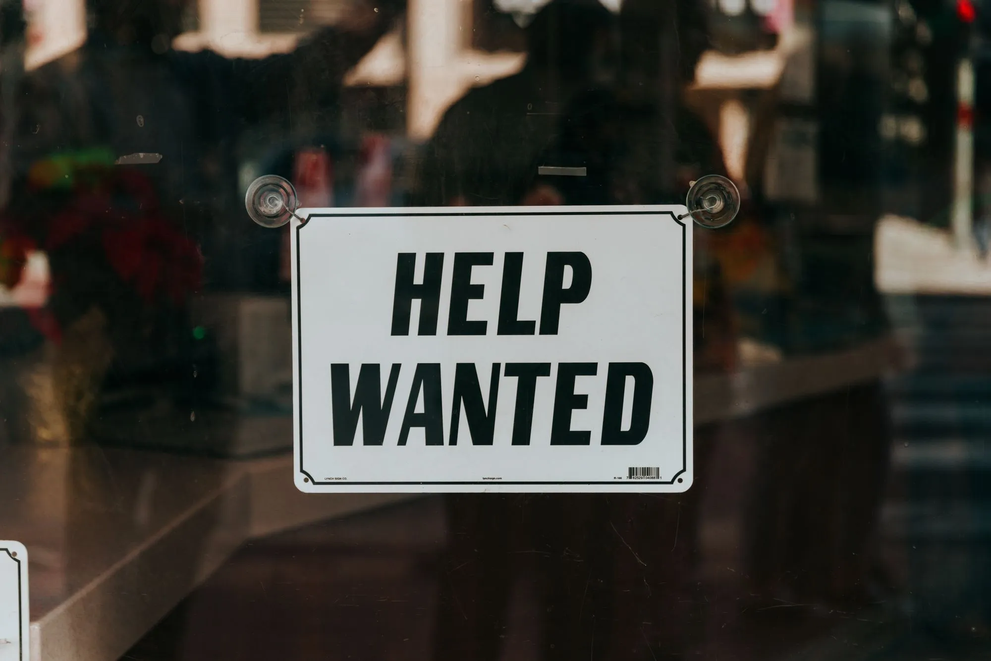 "Help Wanted" sign on a glass window