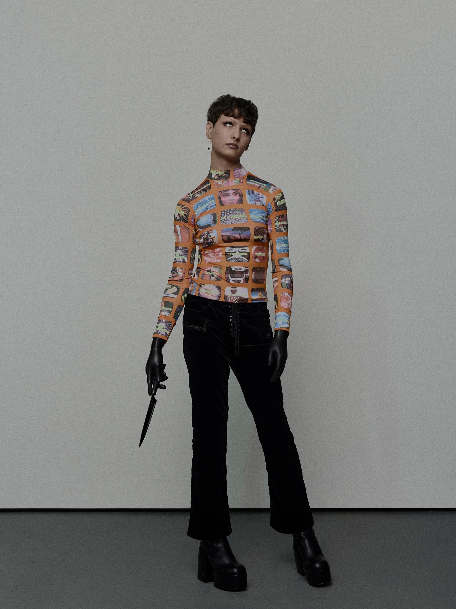 An editorial portrait of a young person, wearing a walter van beirendonck ‘tv trash’ top, latex gloves and holding a knife. The subject is in an expressive, exacerbated pose, with eyes rolled back. Shot in the photo studio in New Orleans, LA. 