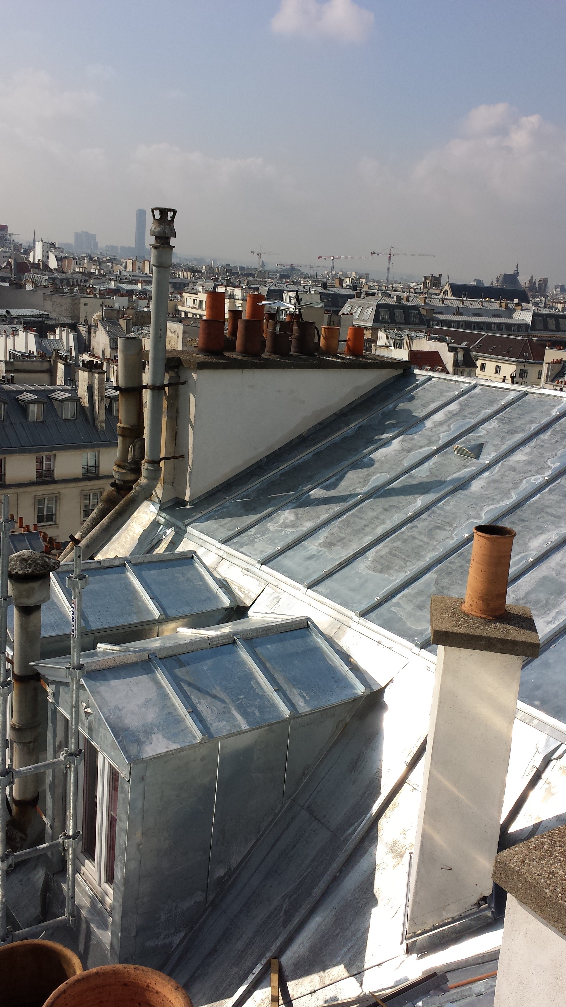 Modern living room with abstract art, beige sectional sofa, indoor plants, and large windows.