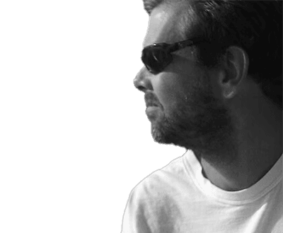 Picture of a man in white jumper with sunglasses next to a lake