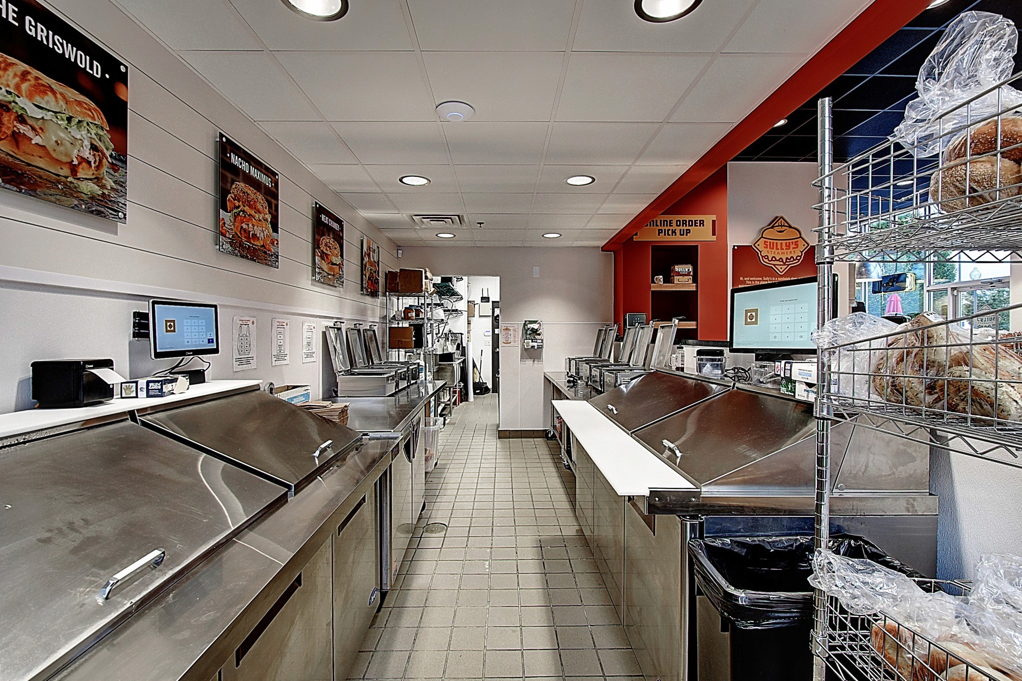 A modern kitche interior with metal counters, vibrant walls, and promotional images on display.