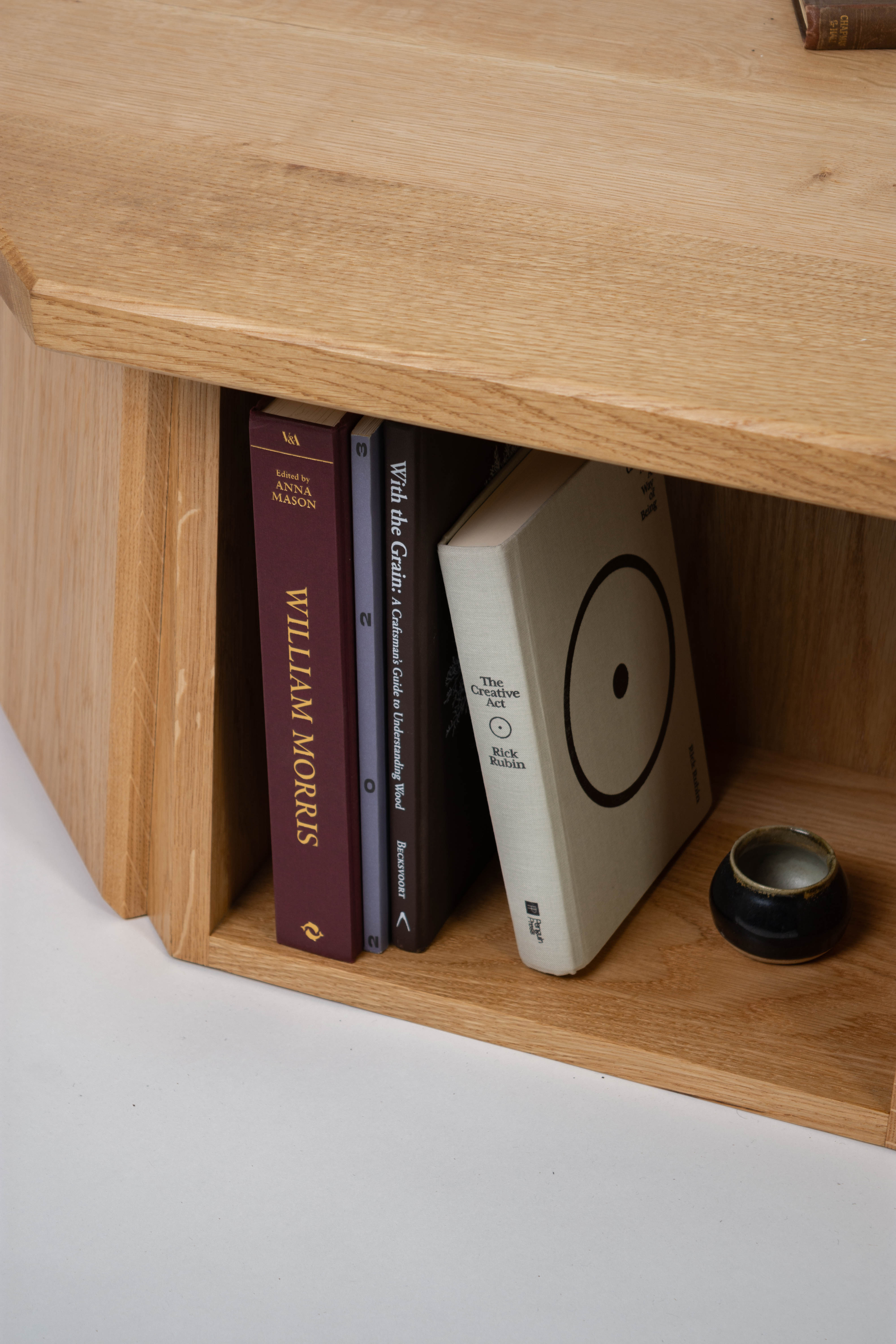 Wooden shelf with books and a small object on a white surface