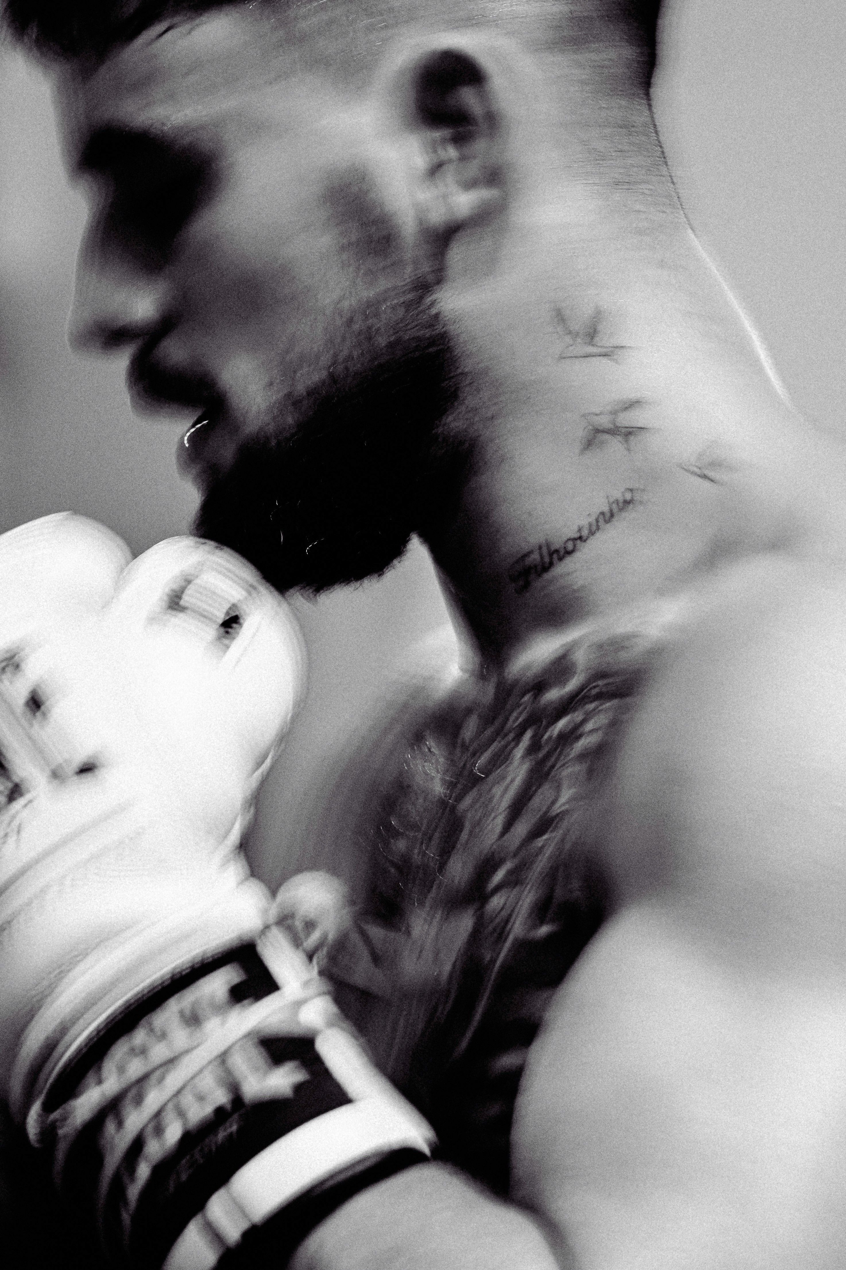 A woman wearing a shiny coat stands in focus, while a blurred background creates a sense of movement.