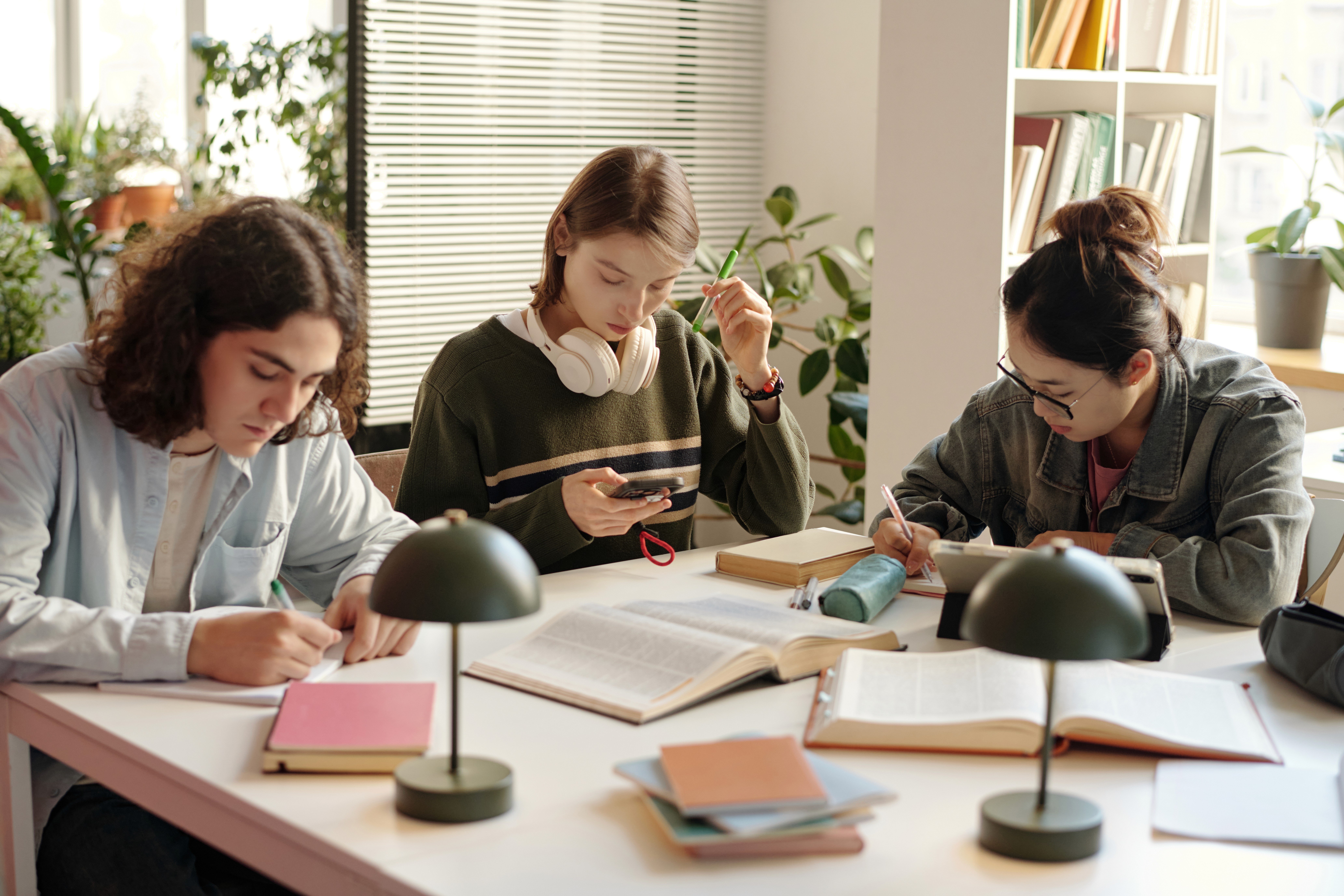Schüler:innen lernen gemeinsam an einem Tisch mit Büchern und Notizen und bereiten sich konzentriert auf Schule und Prüfungen vor