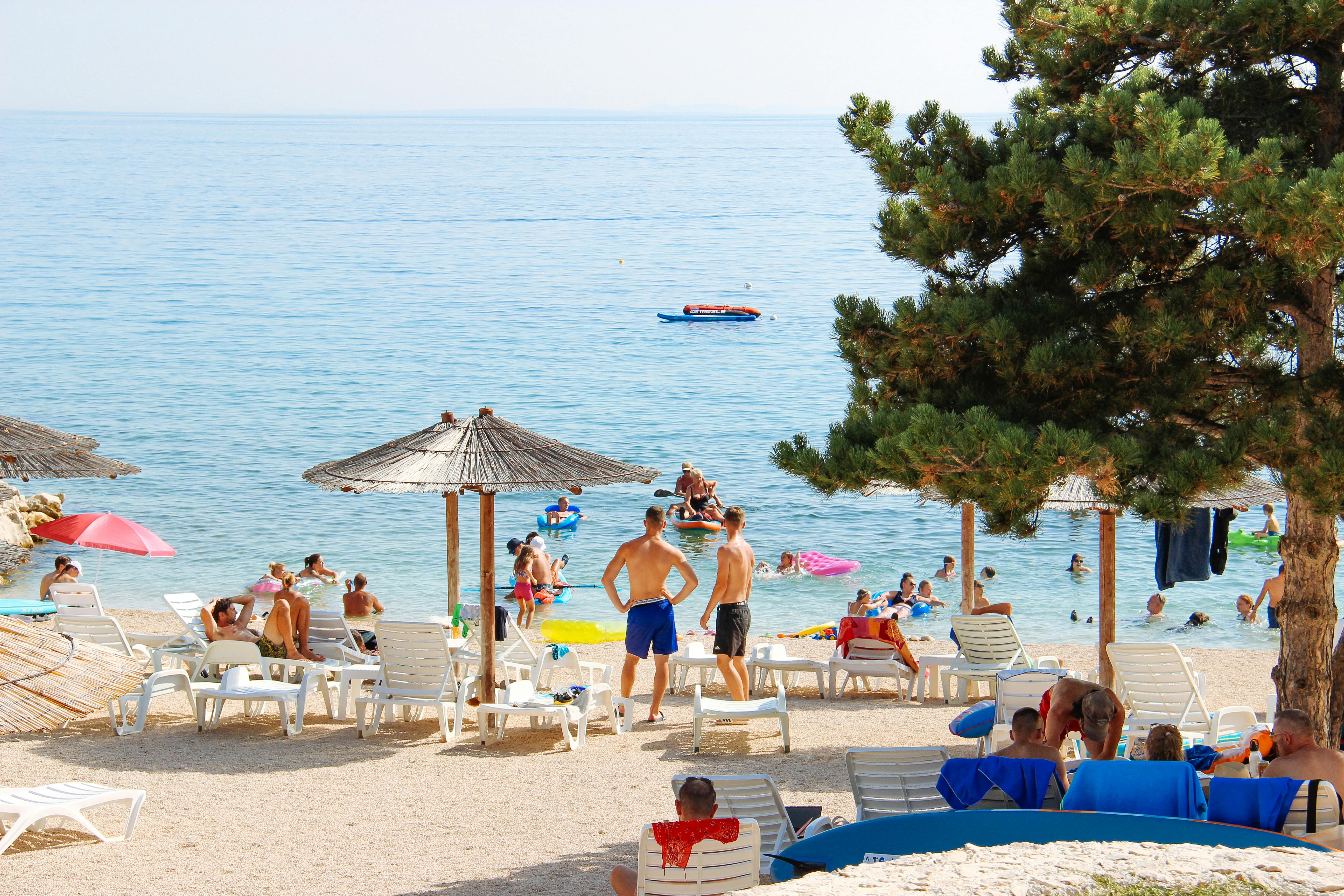 Landscape shot of people relaxing on the beach on lounge chairs.