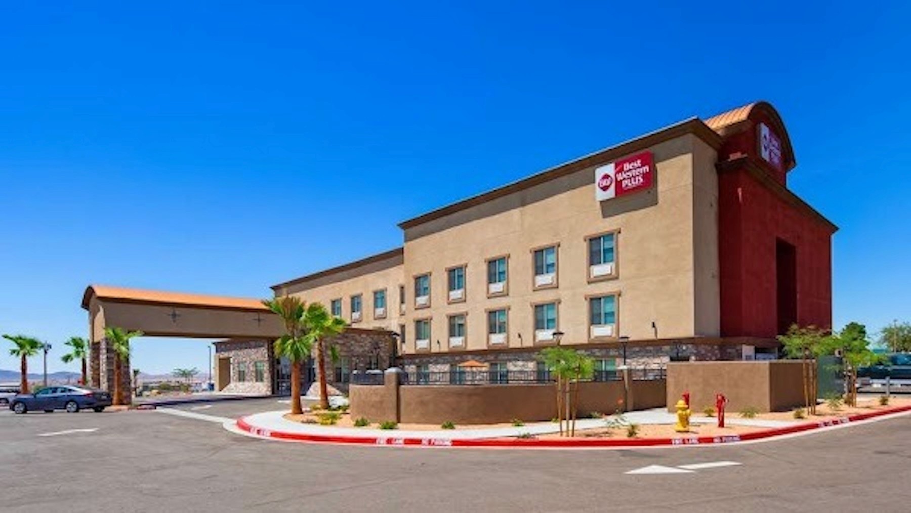 Best Western Plus hotel exterior with covered entrance, landscaped grounds, and parking area under clear skies.
