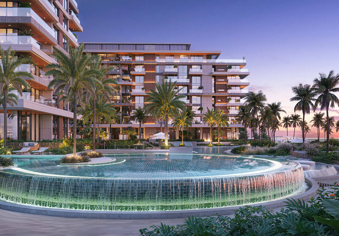 Stunning pool area at Ellington Sands with cascading water, palm trees, and beachfront apartments.