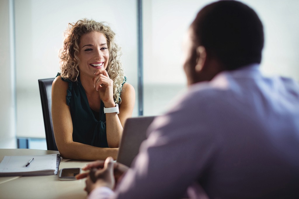 job interview between a woman in a green dress and a man in a purple business shirt