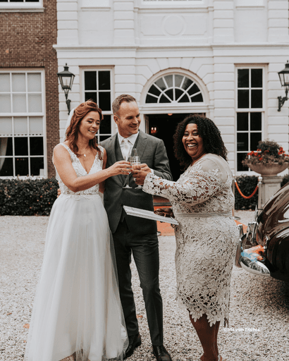 Een zelfstandig trouwambtenaar proost samen met het bruidspaar tijdens hun trouwdag voor een klassieke trouwlocatie — een moment vol liefde en trouwinspiratie.
