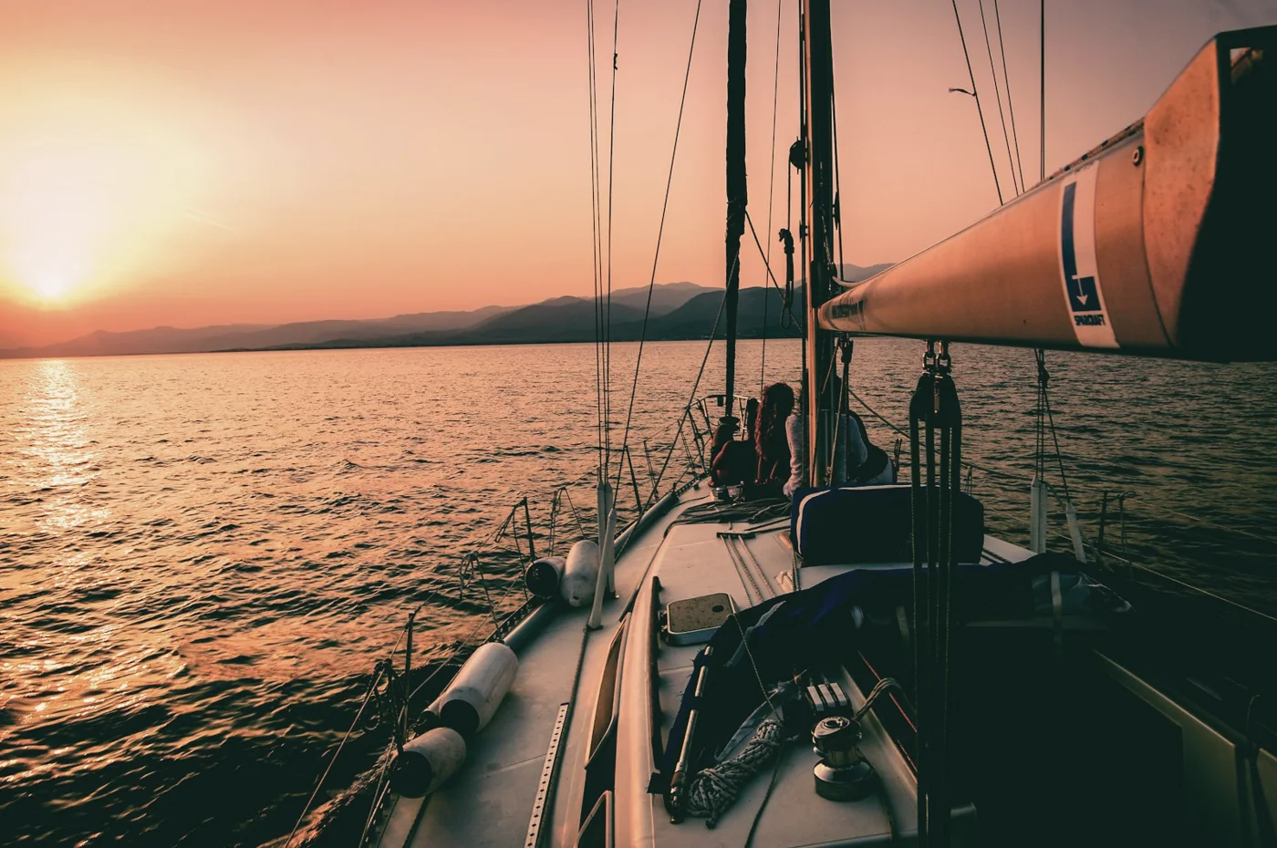 The bow of a sailing boat heading into a sunset
