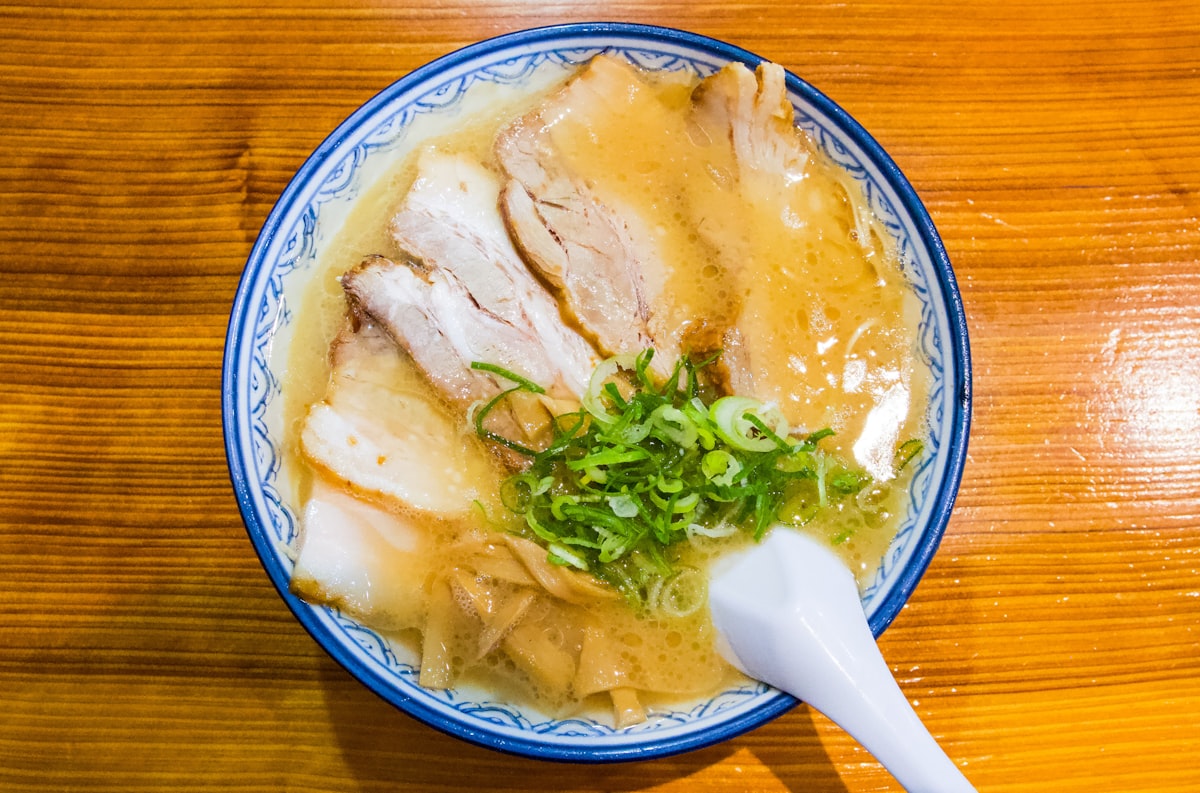 Steaming bowl of tonkotsu ramen with extra pork served at a Japanese noodle shop