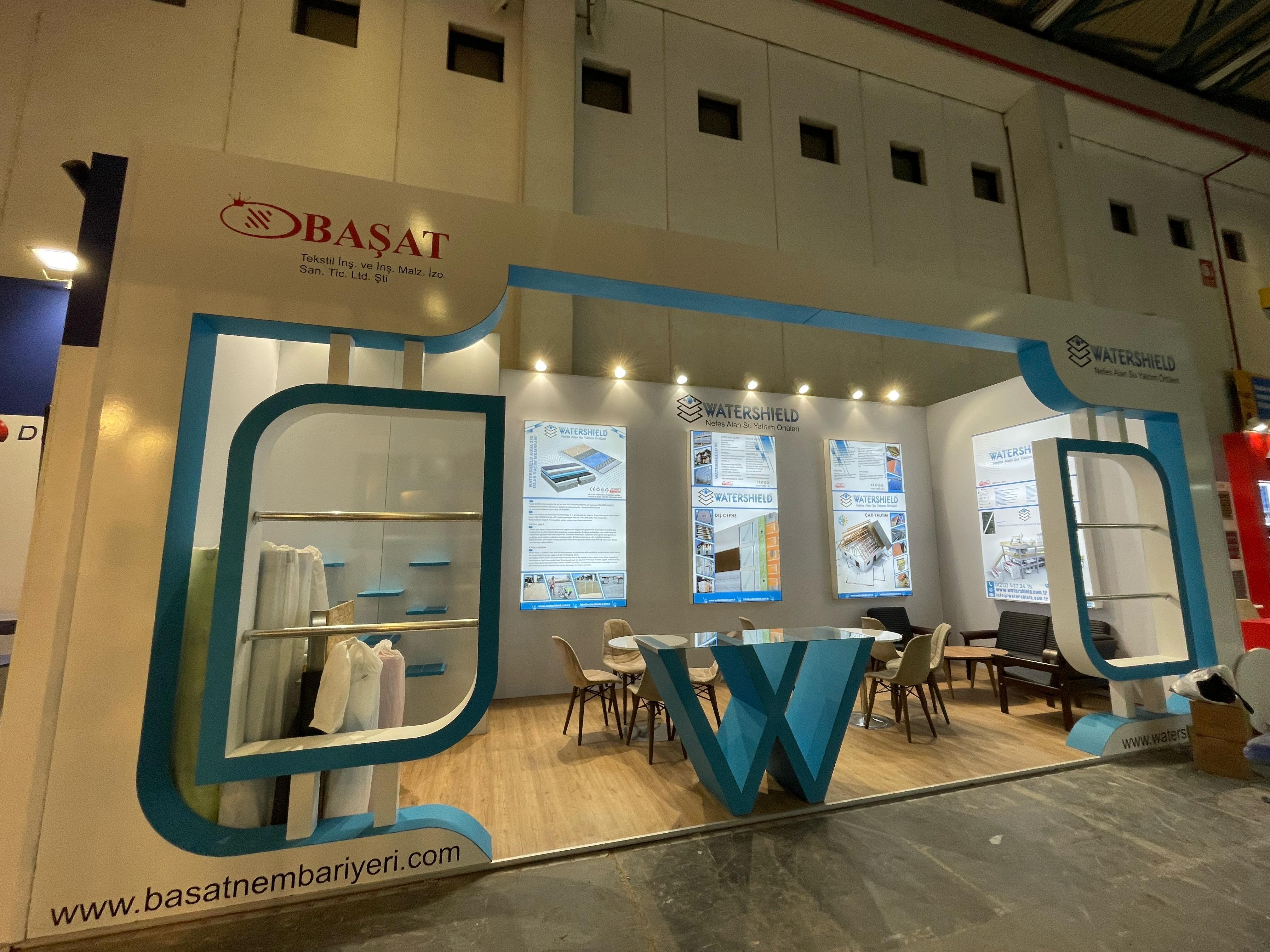 Başat Watershield exhibition stand at Yapı Istanbul 2025, featuring a clean white and blue identity with a large curved blue frame and bold entrance structure.