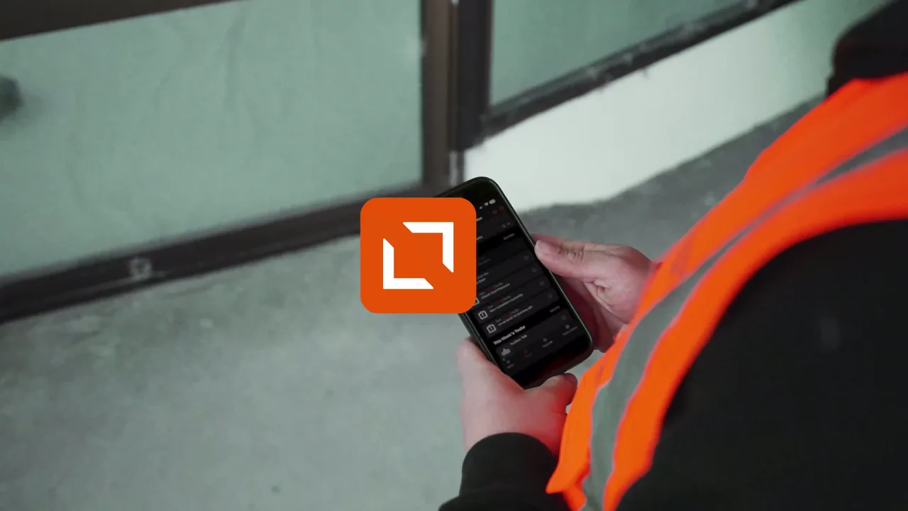 A worker in a hi-vis vest holds a phone as an orange app icon appears