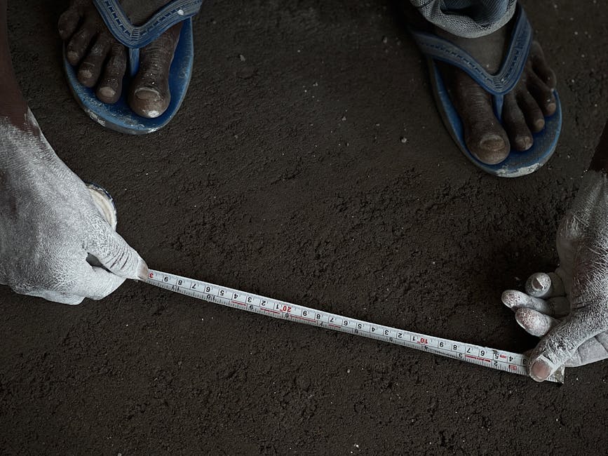 Close-up of a person measuring soil with a tape measure and chalk-covered hands.