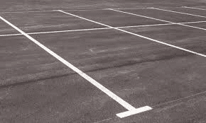 an empty parking lot with a building in the background