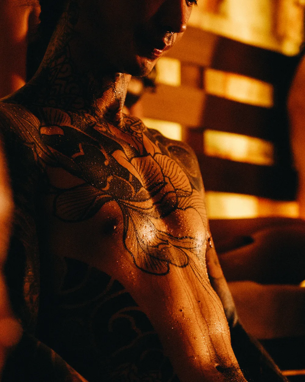 Tattooed man relaxing in a softly lit sauna, reflecting sauna etiquette focused on calmness, hygiene, and mindfulness.