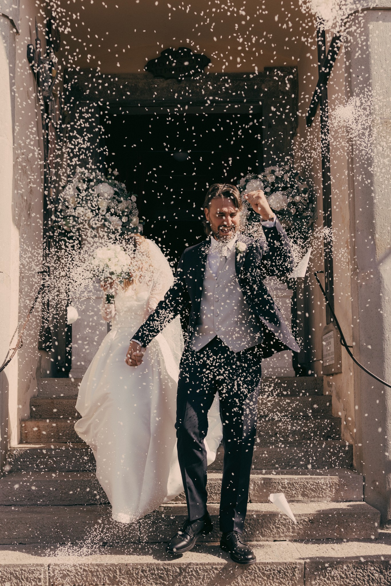 Sposi avvolti da pioggia di riso all'uscita dalla chiesa a Bolgheri, reportage di matrimonio in Toscana