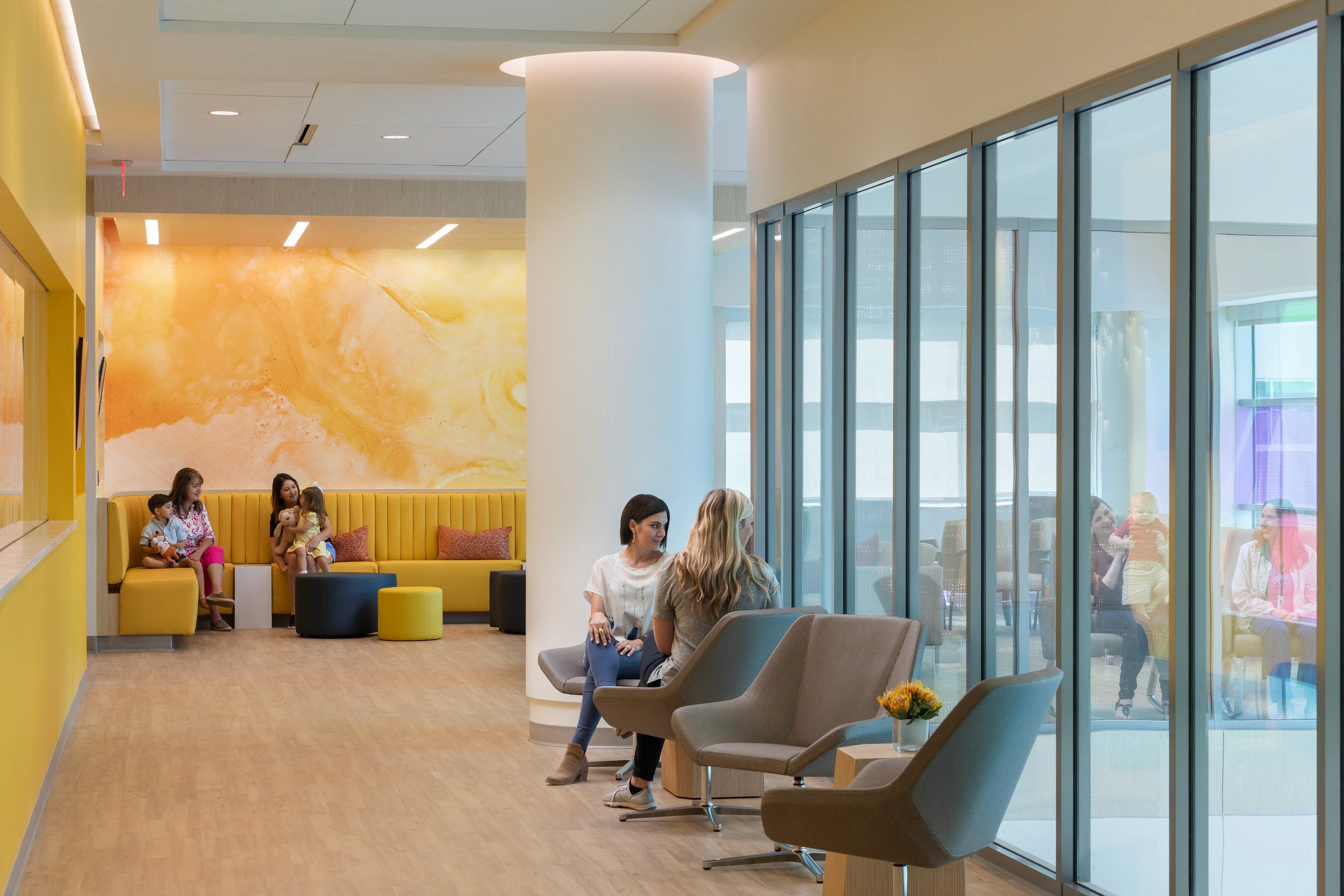 Modern waiting room with yellow accent wall and glass partitions.