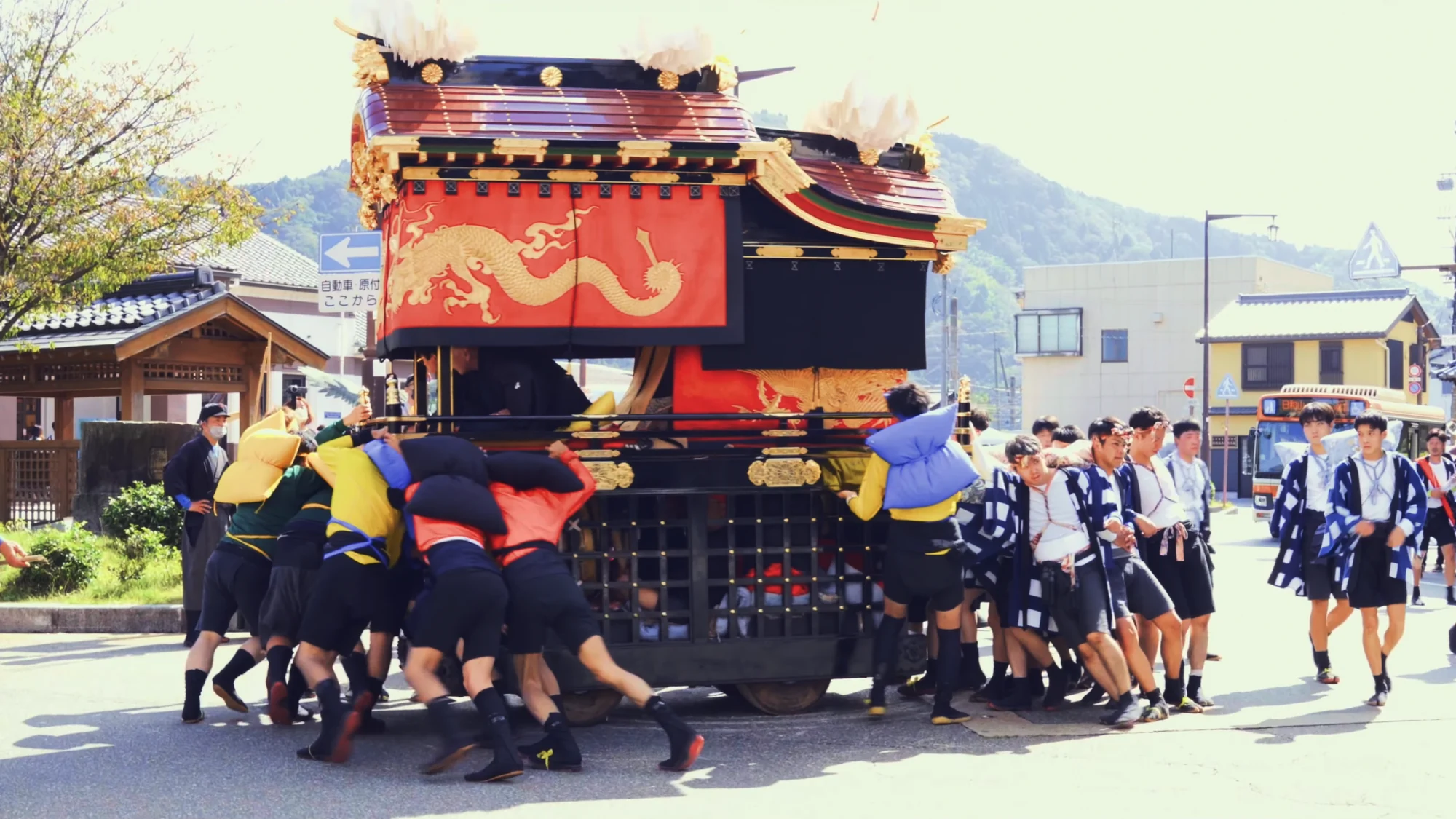 A festival float moving along a Kinosaki street with the crowd following behind.