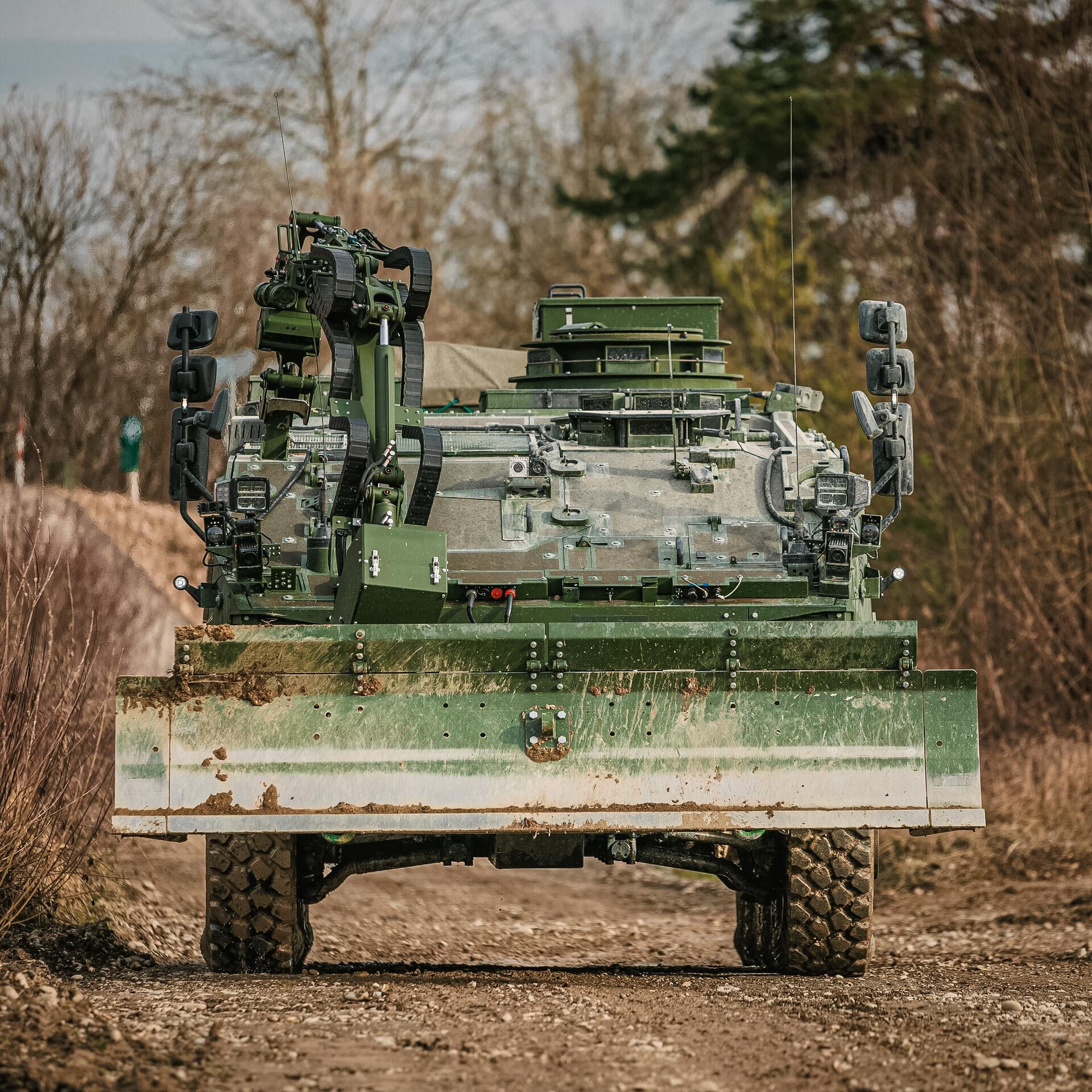 GCS dozer blade with manipulator arm mounted on a Piranha IV wheeled vehicle during route clearance operations.